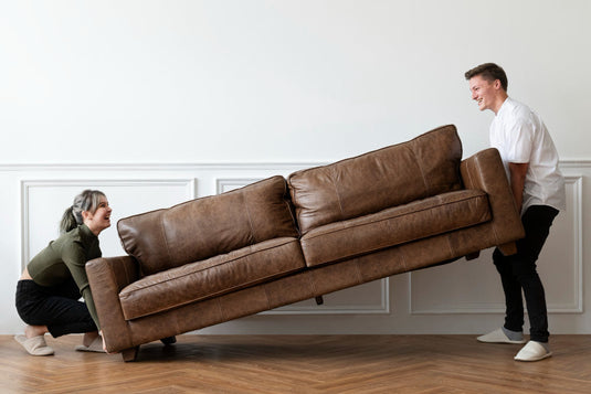 Movers lifting a heavy sofa with proper technique and moving straps