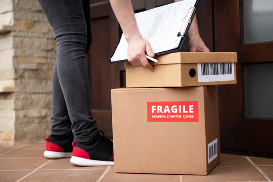 Fragile glassware wrapped in protective packing paper inside a moving box