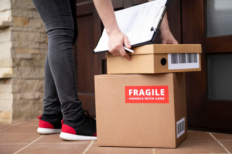 Fragile glassware wrapped in protective packing paper inside a moving box