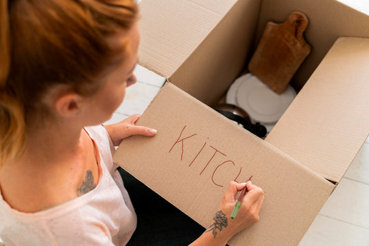 Couple labeling moving boxes by room before their move