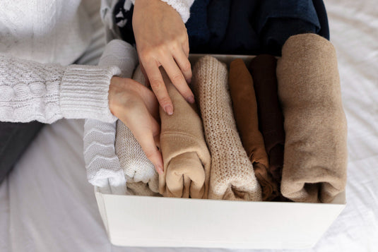Folding and packing clothes into moving boxes and a suitcase