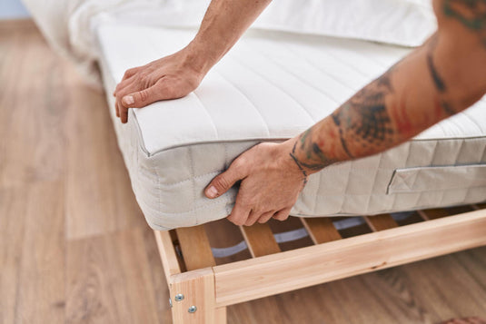 Person carrying a mattress in a protective bag while moving